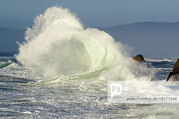 Plätschernde Welle  die sich am Ufer bricht  mit der Küstenlinie von Oregon im Hintergrund am Cape Kiwanda; Oregon  Vereinigte Staaten von Amerika