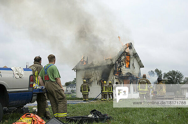 Local fire fighters use a controlled burning of a house for practice; Palmyra  Nebraska  United States of America