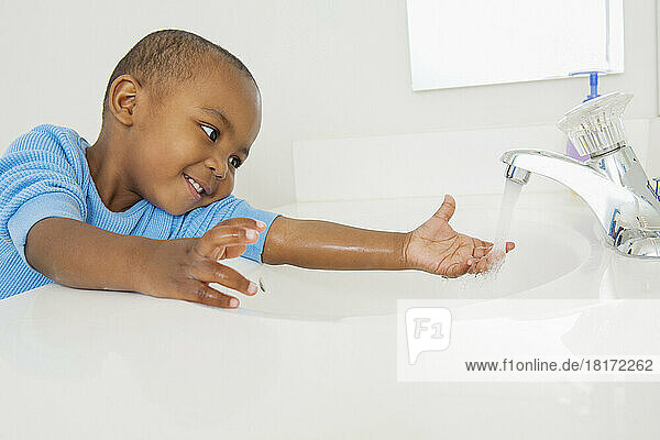 Toddler Washing his Hands in Bathroom Sink