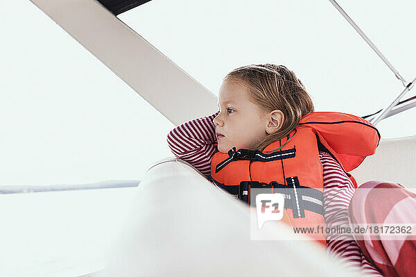 Close-up of 3 year old girl in orange life jacket on a motorboat  Sweden