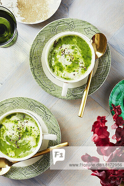 Watercress soup in tea cups with spoons and flowers