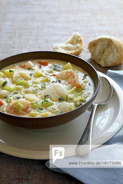 Bowl of seafood chowder soup with a spoon and crusty bread