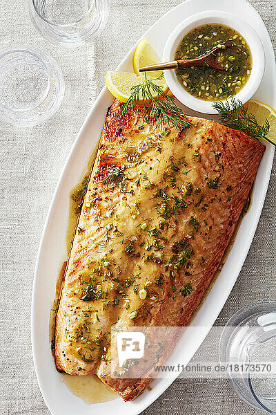 Baked salmon filet with herbed mustard sauce served on a white platter