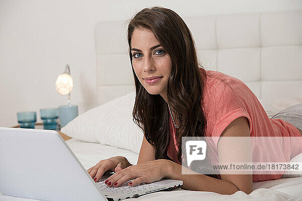 Young Woman using Laptop in Bed