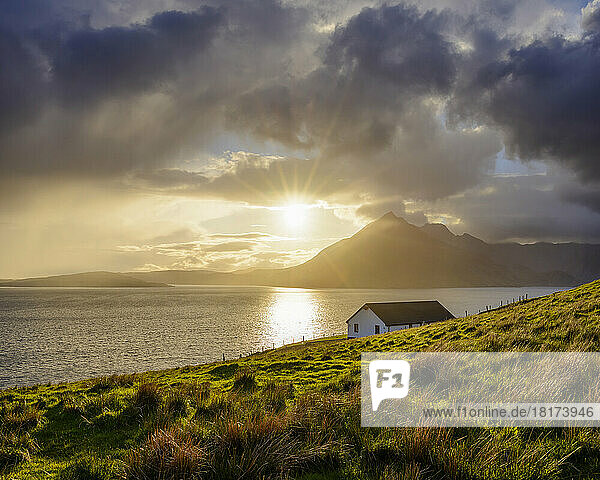Rooftop of a house along the Scottish coast with sun shining through the dramatic clouds over Loch Scavaig on the Isle of Skye in Scotland  United Kingdom