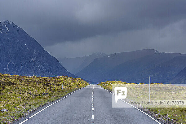 Country road with dark cloudy sky in the highlands on A82 road in Glen Coe  Scotland  United Kingdom