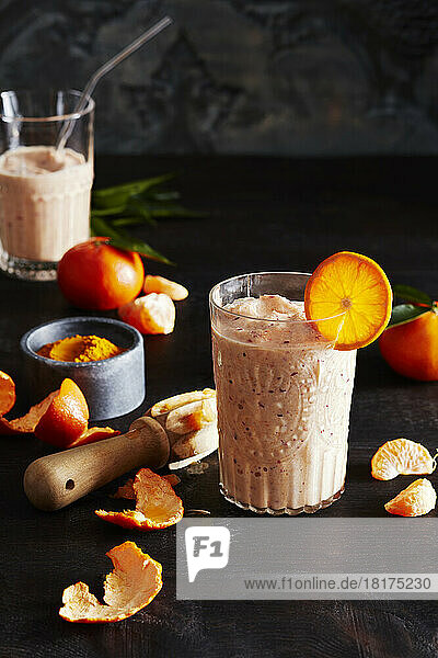 Orange smoothie with orange slices on a dark countertop