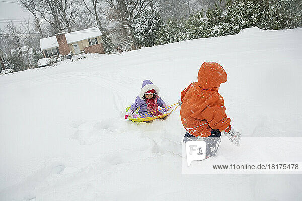 Boy Pulling his little Sister on Sled through Snow  Maryland  USA