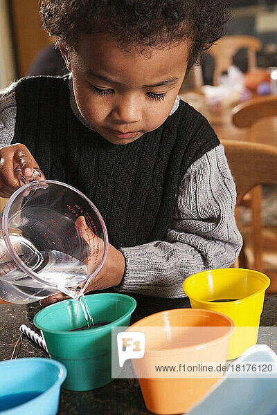 Boy Pouring Water into Dye Cups for Coloring Easter Eggs