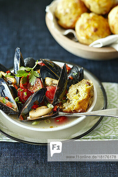 Single Serving of Cooked Fresh Mussels with Tomatoes  Green Onions  Red Peppers and Cilantro with Corn Bread
