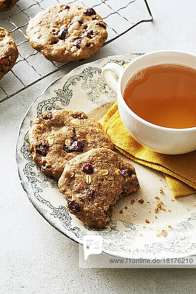 Cranberry oat breakfast cookies on a decorative plate with a cup of herbal tea