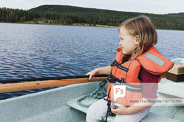 3 year old girl in orange life jacket sitting in a motorboat  fishing  Sweden