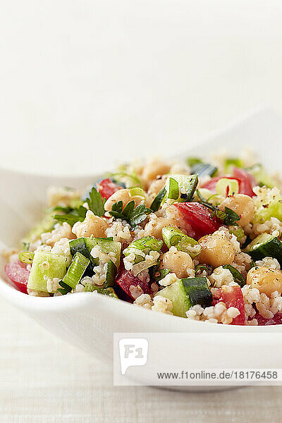 Tabbouleh salad with chickpeas  cucumber and tomatoes in a white bowl
