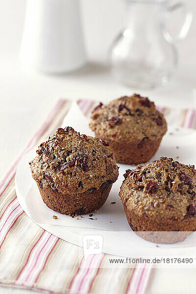 Cranberry flaxseed muffins on a white plate with a striped napkin