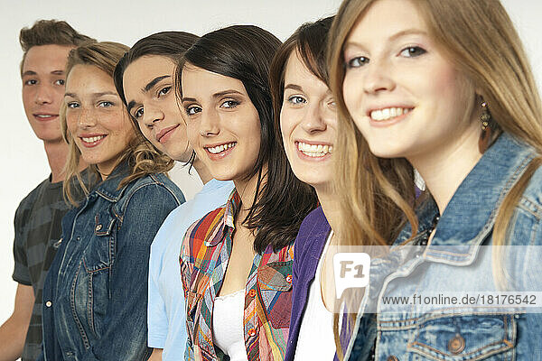 Close-up portrait of six  young men and young women in a row  smiling and looking at camera  studio shot on white background