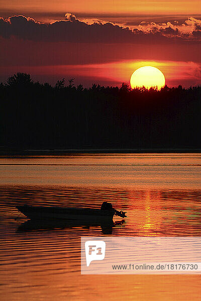 A silhouetted boat at sunset at Cote a Fabien.; Cote a Fabien  Kouchibouguac National Park  Kouchibouguac  New Brunswick  Canada.