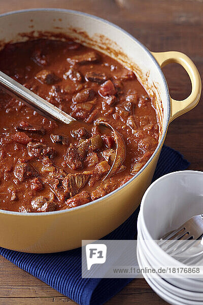 Chunky beef chili in a yellow enamel pot with ladle