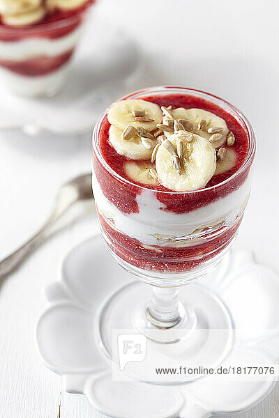 Strawberry banana yogurt parfait with sunflower seeds in a stemmed glass