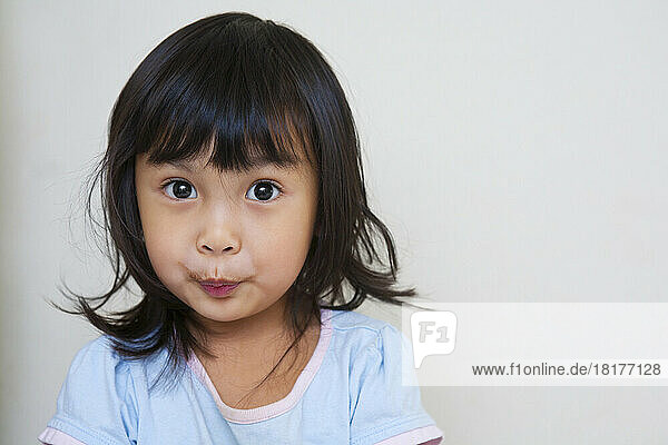 Close-up portrait of Asian toddler girl  looking at camera with surprised expression  studio shot on white background