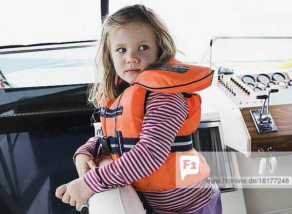 Portrait of 3 year old girl in orange life jacket on a motorboat  Sweden