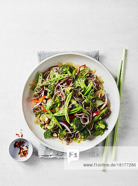 Soba noodle salad with chopsticks and chili flakes