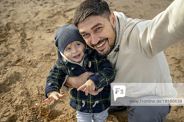 Glücklicher Vater macht Selfie mit Sohn am Strand