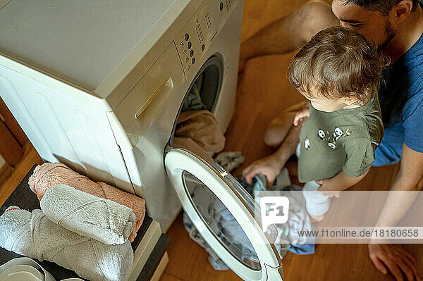 Sohn und Vater laden Kleidung in die Waschmaschine