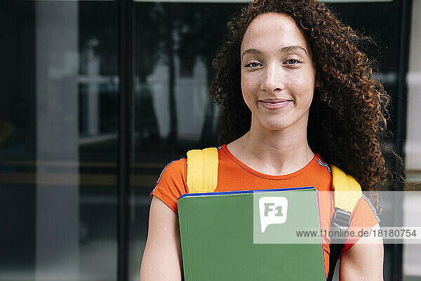 Smiling young woman holding green folder