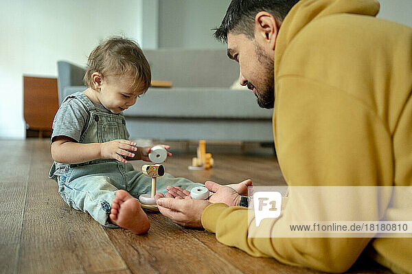 Vater und Sohn spielen mit Holzspielzeug im Wohnzimmer
