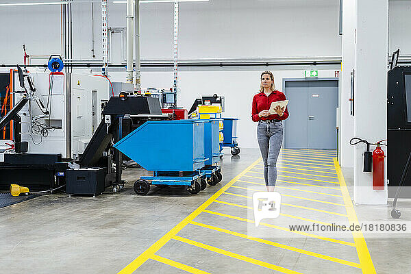 Businesswoman with tablet PC walking on markings in factory