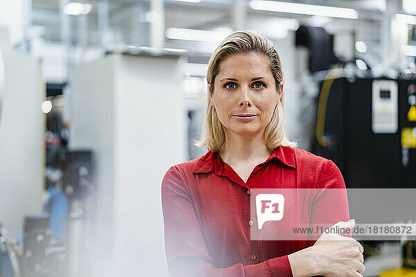 Confident businesswoman with arms crossed at factory