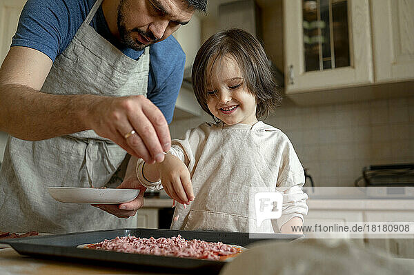 Father with son making pizza in kitchen at home
