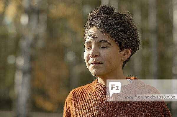 Boy with eyes closed in park