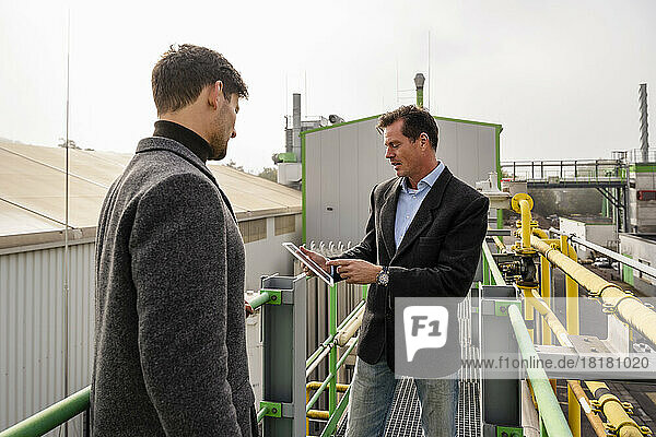 Businessman with colleague using tablet PC at recycling plant