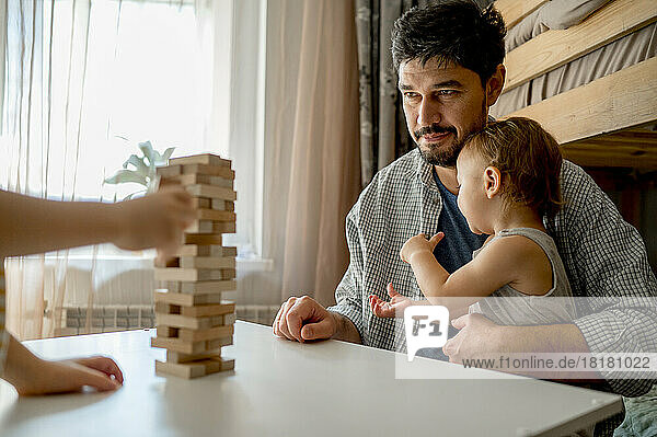 Father with son looking at block removal game on table at home
