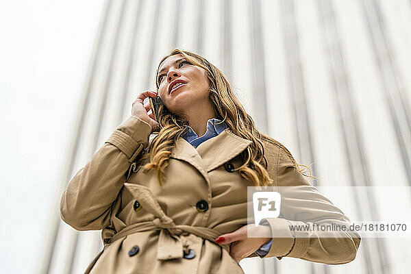 Businesswoman talking on mobile phone in front of building