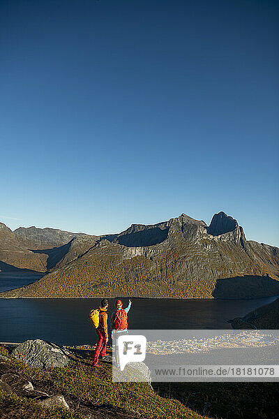 Couple standing at edge of Segla mountain and admiring view
