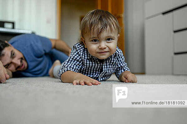 Smiling son with father lying on carpet at home