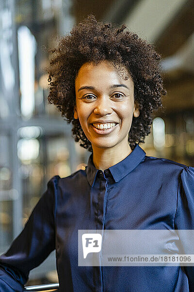 Happy businesswoman with curly hair wearing blue shirt