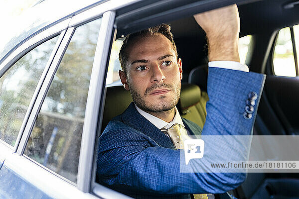 Thoughtful businessman looking out of taxi window