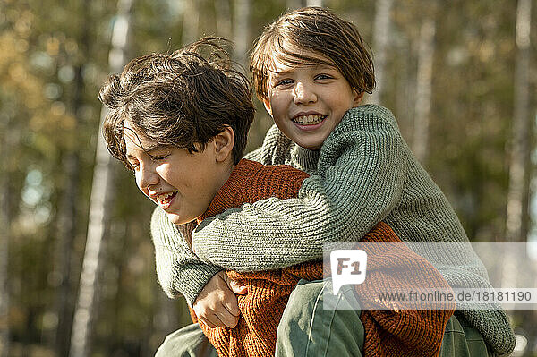Smiling boy giving piggyback ride to brother in park