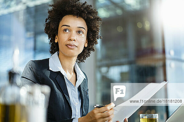 Contemplative businesswoman with document at office