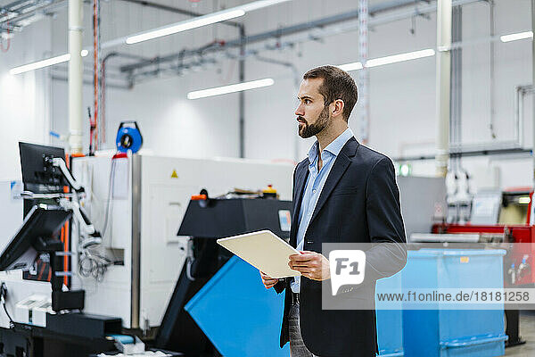 Businessman wearing blazer holding tablet PC at factory