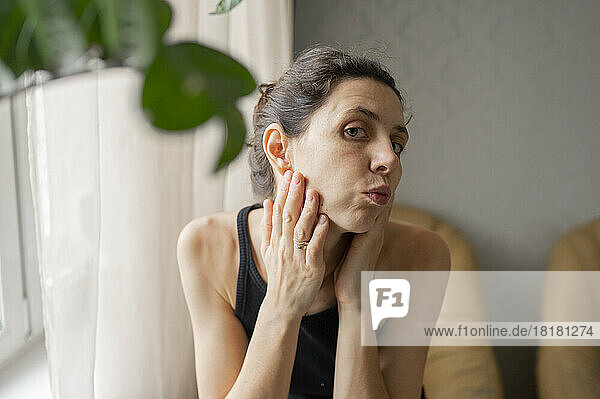 Woman touching facial skin at home