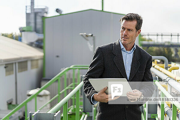 Mature businessman standing with tablet PC