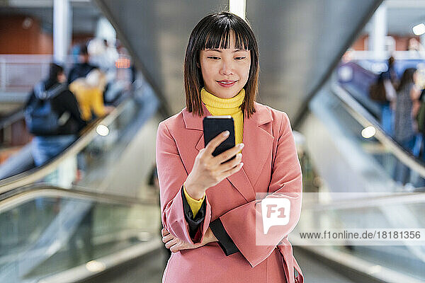 Lächelnde junge Frau  die auf Rolltreppe im Internet surft
