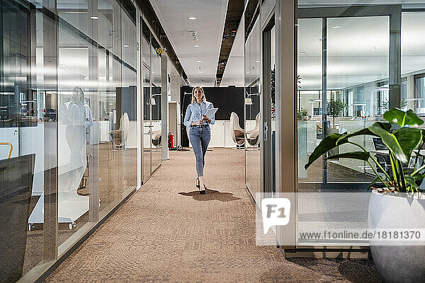 Businesswoman with tablet PC walking at workplace