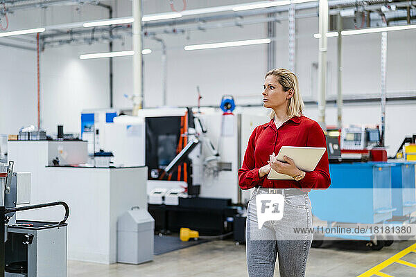 Businesswoman walking with tablet PC in factory