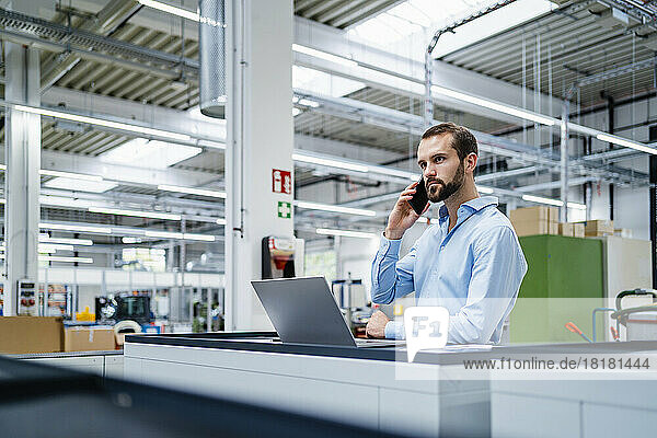 Businessman talking on mobile phone in industry