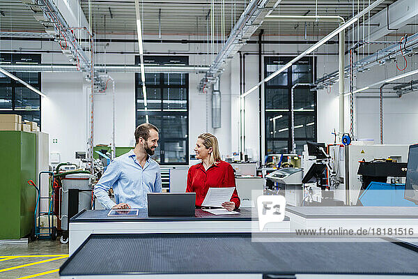 Happy business colleagues talking to each other at factory
